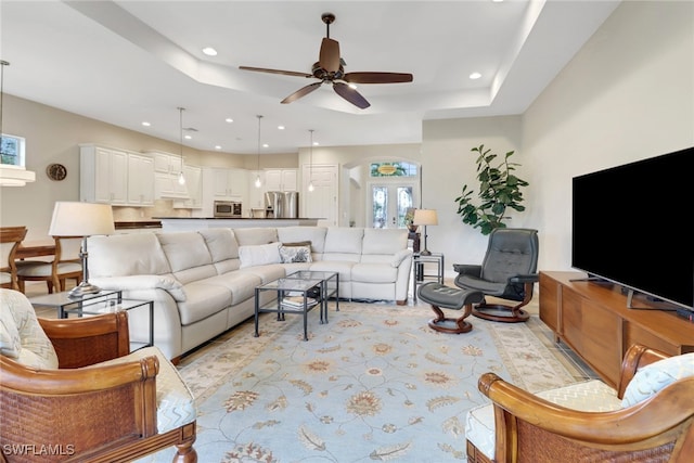 living room featuring ceiling fan, a raised ceiling, and french doors