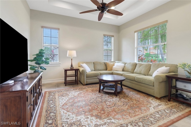 living room with ceiling fan, light tile patterned floors, and a tray ceiling