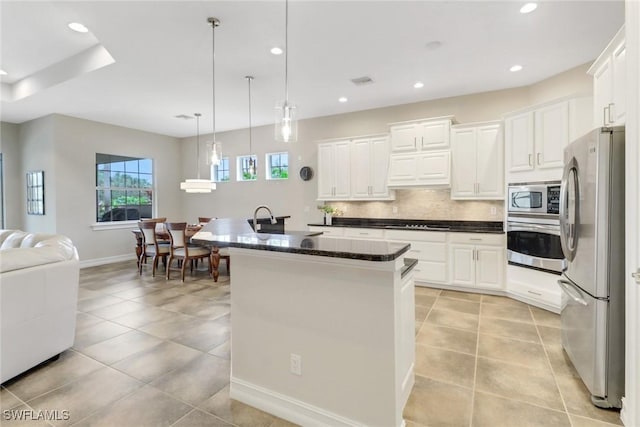 kitchen with white cabinetry, hanging light fixtures, stainless steel appliances, and an island with sink