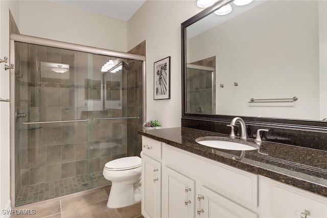 bathroom with tile patterned flooring, toilet, walk in shower, and vanity