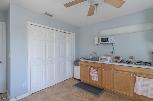 kitchen featuring ceiling fan, stainless steel gas stovetop, and sink