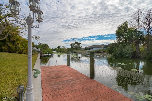 dock area featuring a water view and a lawn