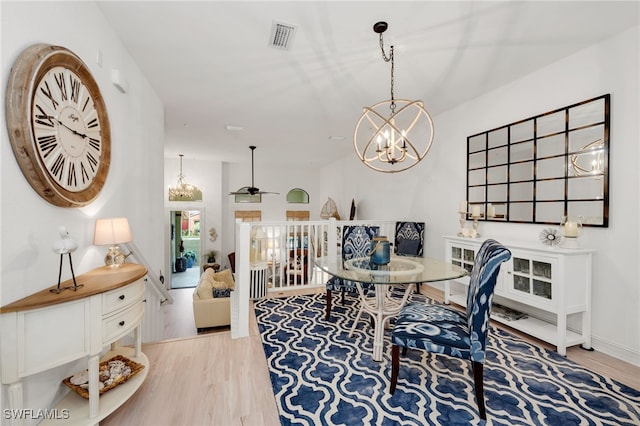 dining area featuring ceiling fan with notable chandelier and light hardwood / wood-style flooring