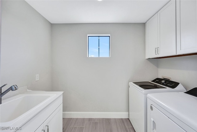 clothes washing area featuring washing machine and dryer, cabinets, and sink