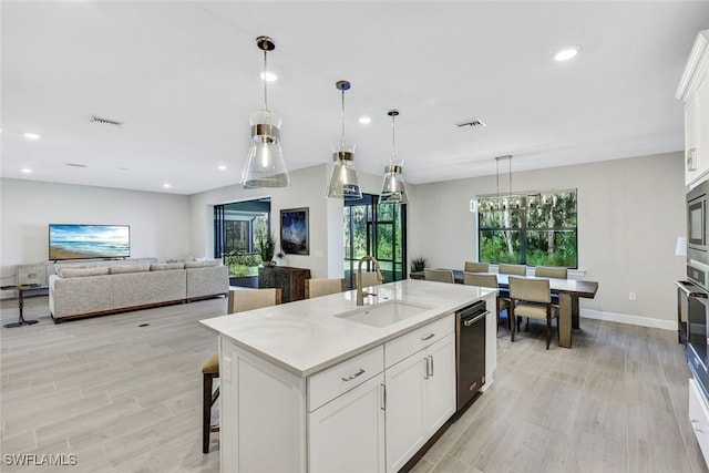 kitchen featuring sink, an island with sink, white cabinetry, and pendant lighting