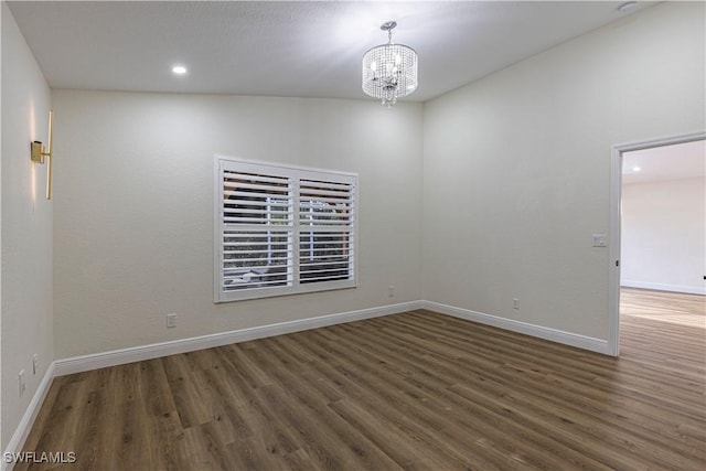 unfurnished room featuring an inviting chandelier and dark hardwood / wood-style flooring