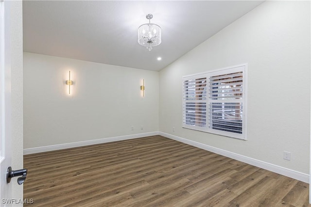 unfurnished room featuring dark hardwood / wood-style flooring, lofted ceiling, and an inviting chandelier