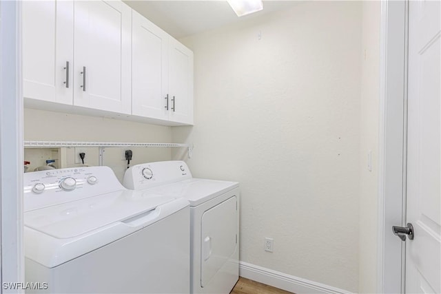 washroom featuring cabinets, separate washer and dryer, and light hardwood / wood-style flooring