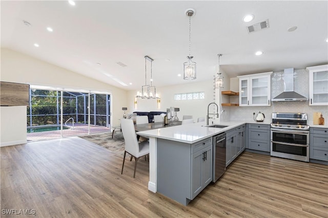 kitchen with appliances with stainless steel finishes, wall chimney exhaust hood, decorative backsplash, sink, and gray cabinets