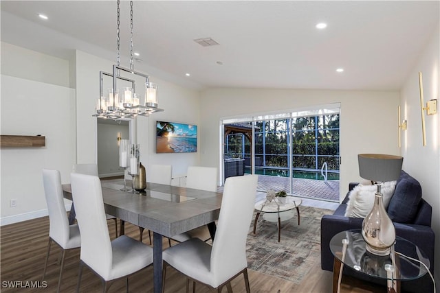 dining space featuring dark hardwood / wood-style floors, an inviting chandelier, and vaulted ceiling