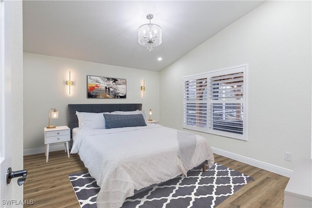 bedroom with vaulted ceiling, an inviting chandelier, and dark hardwood / wood-style floors