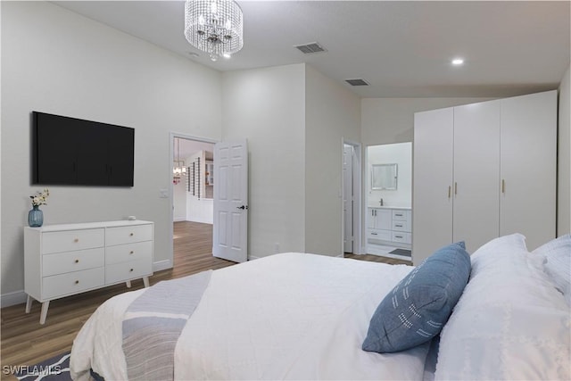 bedroom featuring high vaulted ceiling, dark hardwood / wood-style flooring, ensuite bath, and an inviting chandelier