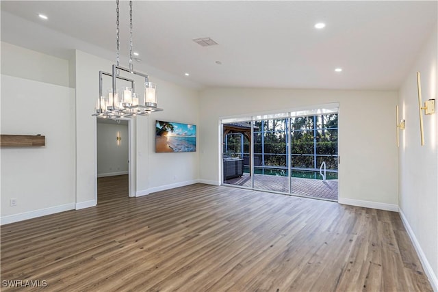 unfurnished dining area with hardwood / wood-style floors, a chandelier, and lofted ceiling