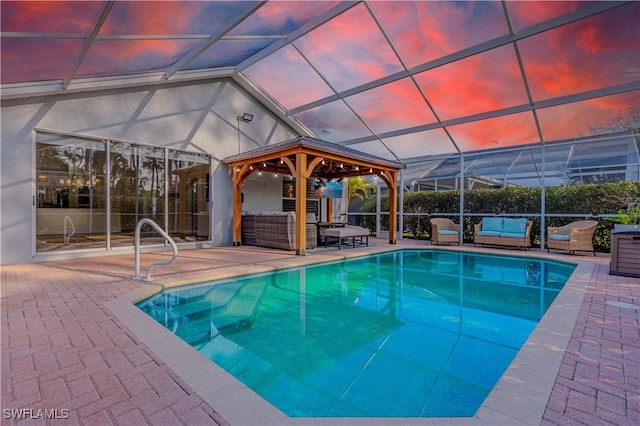 pool at dusk with an outdoor living space, a gazebo, a lanai, and a patio area