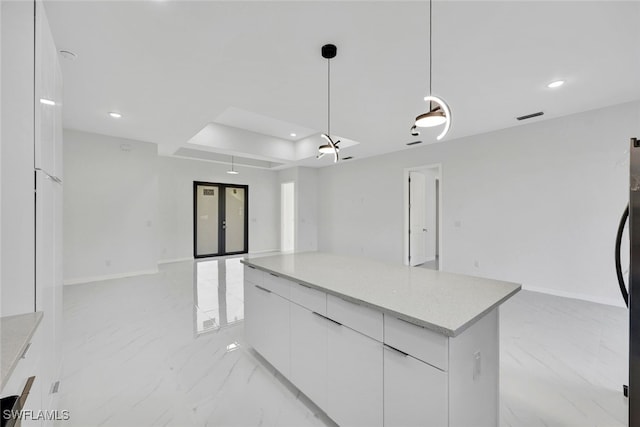 kitchen featuring french doors, hanging light fixtures, a tray ceiling, a kitchen island, and white cabinets