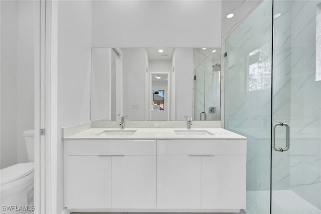 bathroom with vanity, a shower with door, and toilet