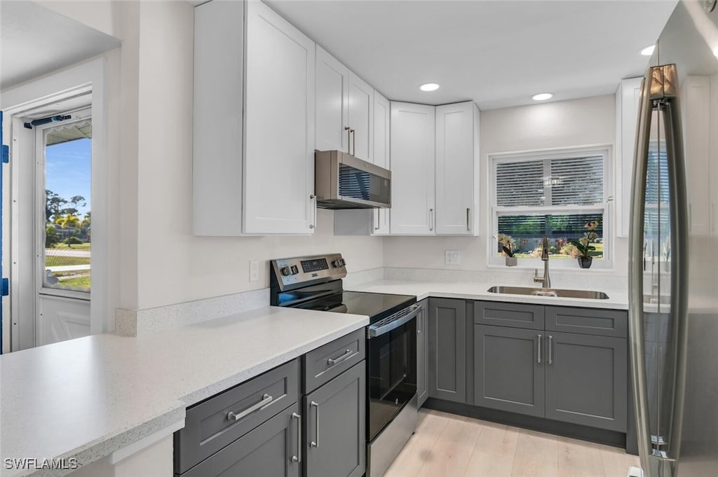 kitchen featuring gray cabinets, stainless steel appliances, white cabinetry, and sink