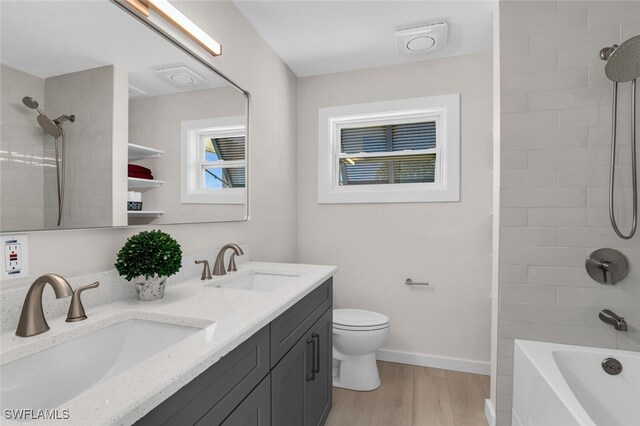 full bathroom with wood-type flooring, toilet, vanity, and tiled shower / bath combo