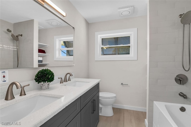 full bathroom with hardwood / wood-style flooring, toilet, vanity, and tiled shower / bath