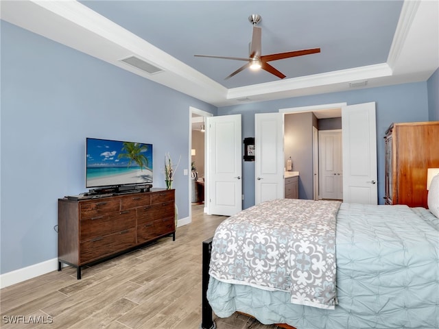 bedroom with ensuite bath, hardwood / wood-style flooring, ornamental molding, a raised ceiling, and ceiling fan