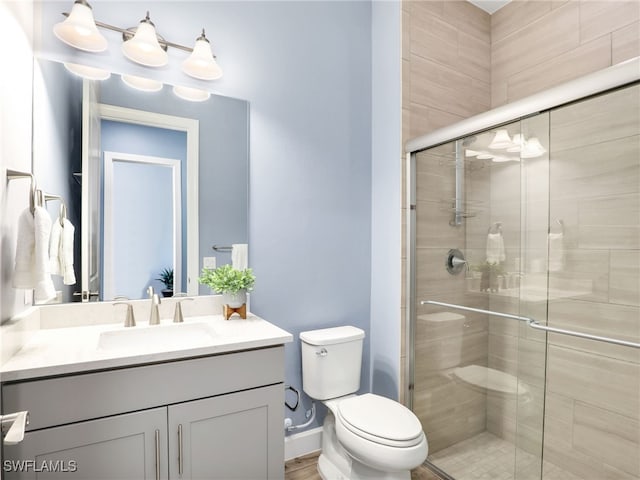 bathroom with a shower with shower door, toilet, and vanity