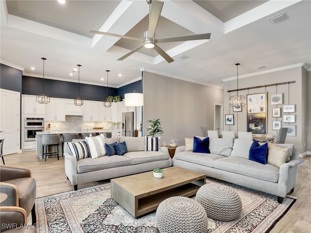 living room with ornamental molding, light hardwood / wood-style floors, ceiling fan with notable chandelier, and coffered ceiling