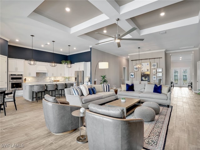 living room featuring ceiling fan with notable chandelier, sink, light hardwood / wood-style flooring, and coffered ceiling