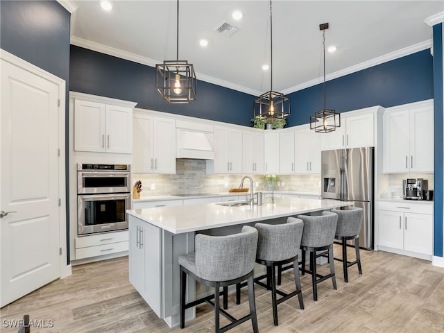 kitchen featuring an island with sink, white cabinets, appliances with stainless steel finishes, and sink