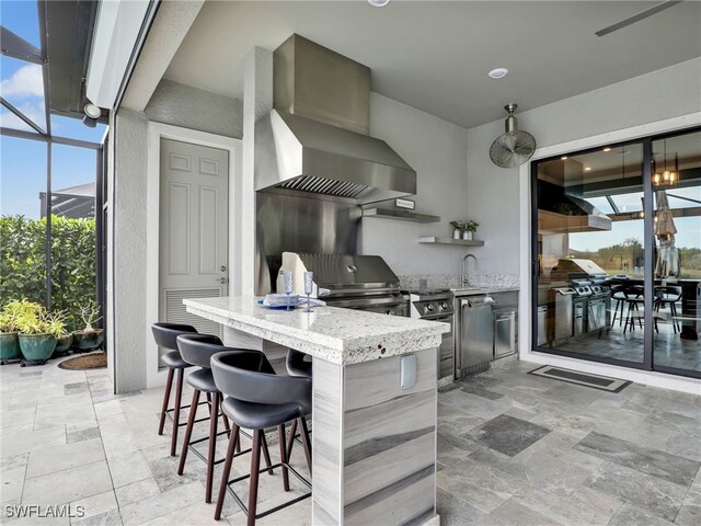 view of patio with glass enclosure, an outdoor kitchen, and a wet bar