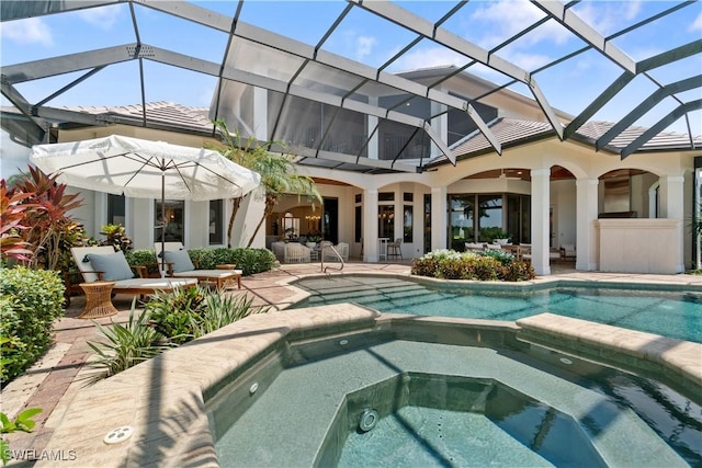 view of pool with a patio, glass enclosure, and an in ground hot tub