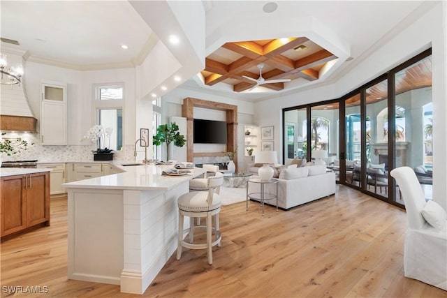 kitchen featuring a breakfast bar, tasteful backsplash, sink, coffered ceiling, and kitchen peninsula