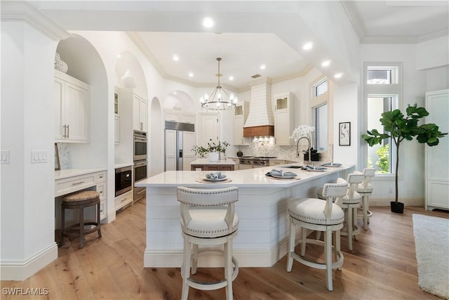 kitchen featuring paneled built in refrigerator, hanging light fixtures, white cabinets, a kitchen bar, and kitchen peninsula