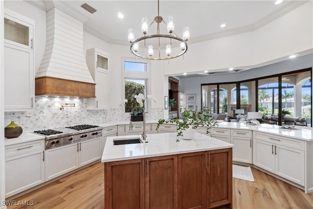 kitchen featuring white cabinetry, sink, a center island with sink, and pendant lighting