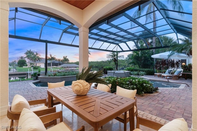 patio terrace at dusk with a swimming pool with hot tub and a lanai