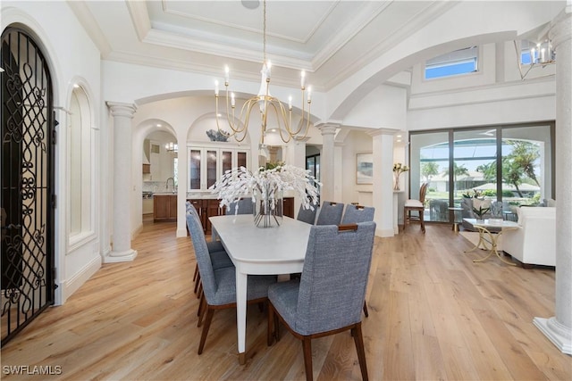 dining area with sink, an inviting chandelier, ornamental molding, light hardwood / wood-style floors, and ornate columns