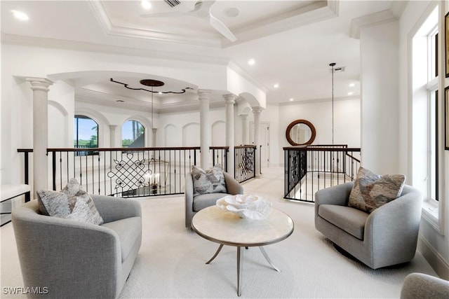 carpeted living room featuring crown molding, ceiling fan, a tray ceiling, and ornate columns