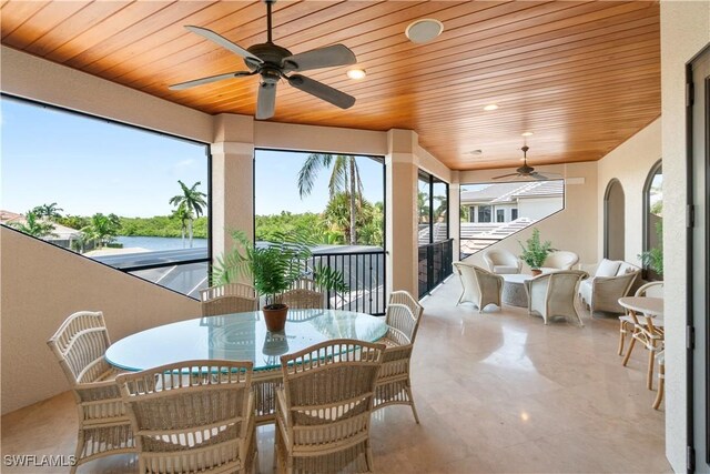 sunroom featuring wood ceiling, ceiling fan, and a water view