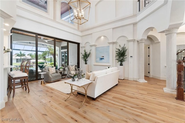 living room with a notable chandelier, light hardwood / wood-style flooring, and ornate columns