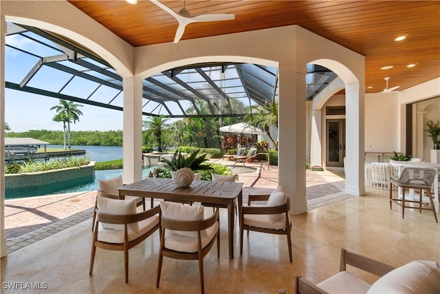 view of patio featuring a water view, ceiling fan, and a lanai