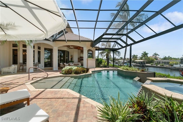 view of swimming pool featuring ceiling fan, a water view, glass enclosure, a patio area, and an in ground hot tub