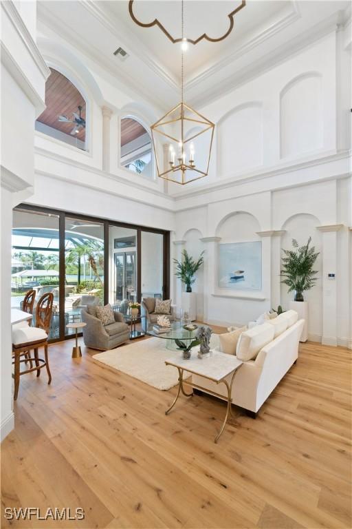 living room featuring a high ceiling, crown molding, wood-type flooring, and a chandelier