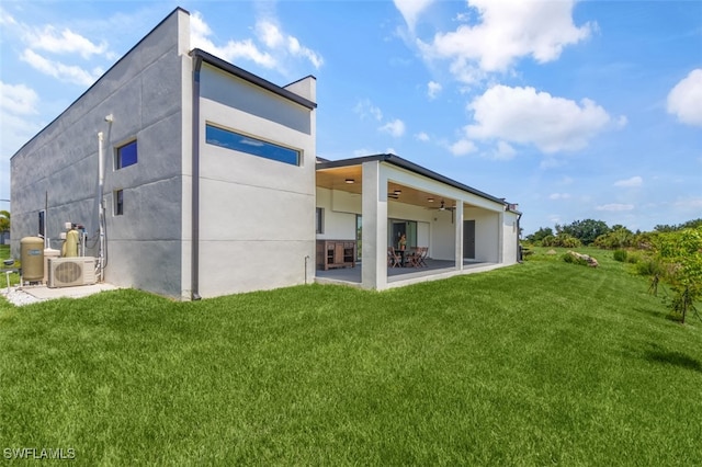 back of house with ac unit, ceiling fan, a lawn, and a patio