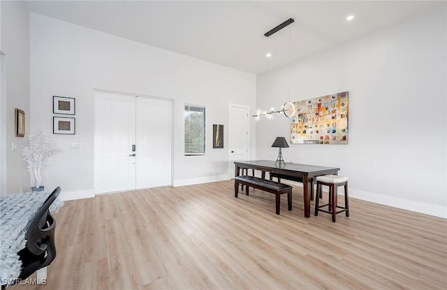 dining area with light wood-type flooring and a high ceiling