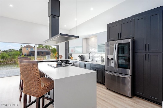 kitchen with stainless steel fridge with ice dispenser, a kitchen bar, a kitchen island, light hardwood / wood-style flooring, and sink