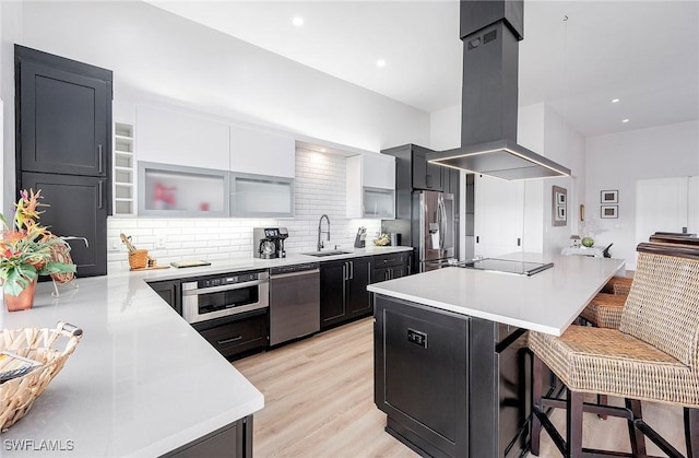 kitchen with appliances with stainless steel finishes, sink, kitchen peninsula, island range hood, and a breakfast bar