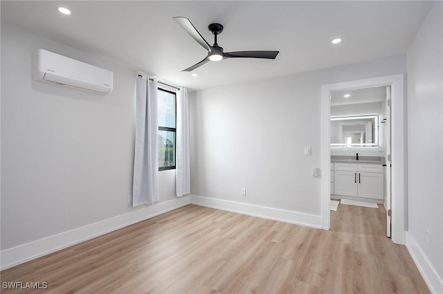 empty room featuring light hardwood / wood-style floors, sink, a wall unit AC, and ceiling fan