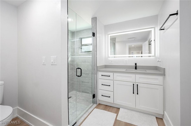 bathroom with toilet, a shower with door, hardwood / wood-style floors, and vanity