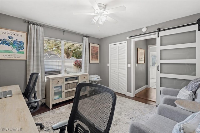 office area featuring ceiling fan, wood-type flooring, and a barn door