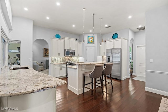 kitchen featuring stainless steel appliances, tasteful backsplash, dark wood-type flooring, white cabinets, and sink