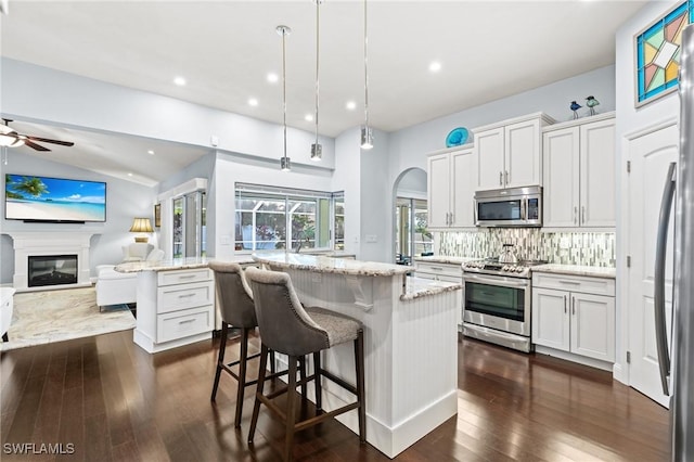 kitchen featuring white cabinetry, stainless steel appliances, tasteful backsplash, and a kitchen island